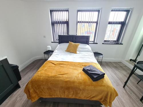 Batley CarrHomestay by BIC Legends 3的一间卧室配有一张带黄毯的床和两个窗户