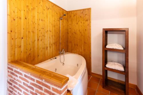 Villavieja del LozoyaHospedería el arco的带浴缸和木墙的浴室