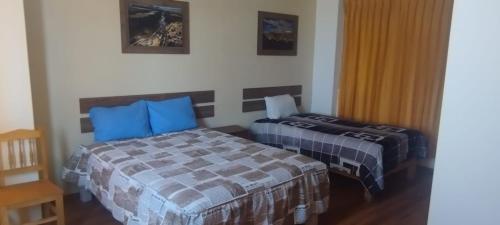 EspinarHostal Los Andes - Espinar的一间卧室配有两张带蓝色枕头的床
