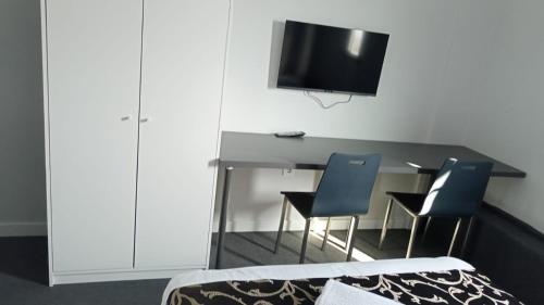 AksuRED FLAG HOTEL的一间卧室配有一张桌子、两把椅子和一台电视