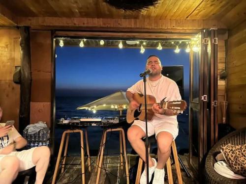 巴尔Hotel Prana Beach的坐在酒吧里弹吉他的人