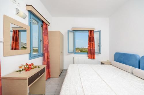 纳克索乔拉Apartments Naxos Camping的一间卧室设有一张床和两个窗户。