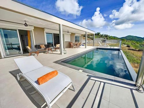 圣马丁岛Villa Grand Horizon with extraordinary 180 degree sea view的一座带游泳池和白色椅子的房子