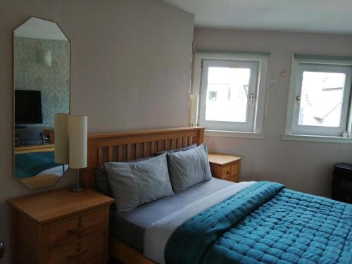 格拉斯哥Aigas的一间卧室配有一张带蓝色毯子的床和两个窗户。