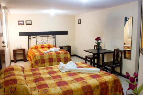 乔卢拉Villas Hotel Cholula的酒店客房设有两张床和一张桌子。