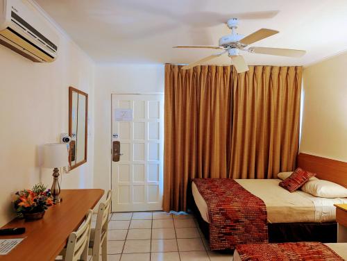 棕榈滩佐佐木公寓的一间卧室配有两张床、一张桌子和吊扇