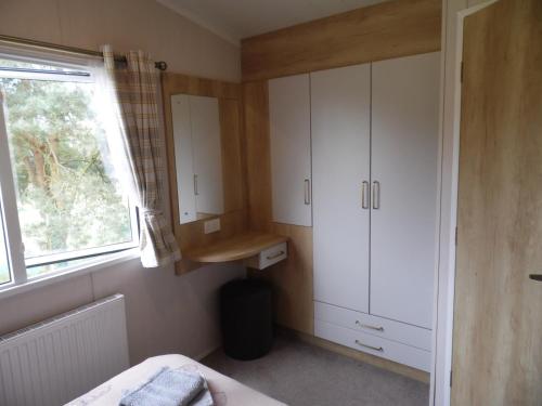 大雅茅斯Stag Lodge的一间小卧室,配有白色的橱柜和窗户
