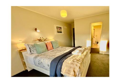 陶朗加Free-Range On Papmoa Beach的一间卧室配有一张带色彩缤纷枕头的大床