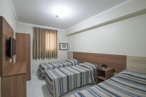 瓜鲁雅Hotel Guarumar Gold的酒店客房设有两张床和电视。