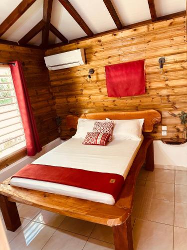 Rivière-PiloteHoney House的木制客房内的一间卧室,配有一张床