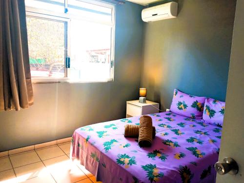 哈皮蒂MOOREA - Fare Taina Iti的一间卧室配有一张带紫色棉被的床和窗户。