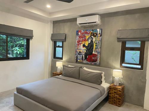 苏梅岛PATAMAAN COTTAGES的卧室配有一张床,墙上挂有绘画作品