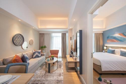 马尼拉Citadines Roces Quezon City的酒店客房,配有床和沙发