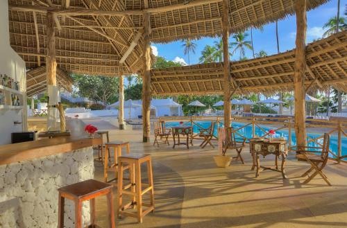 吉汶瓦Diamonds Mapenzi Beach的一个带桌椅的度假村和一个游泳池