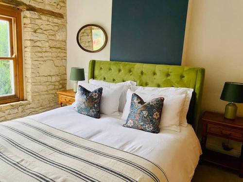 奇平诺顿Cotswold Home over 4 floors - perfect for Families Friends Contractors的一间卧室配有一张带绿色床头板和枕头的床。