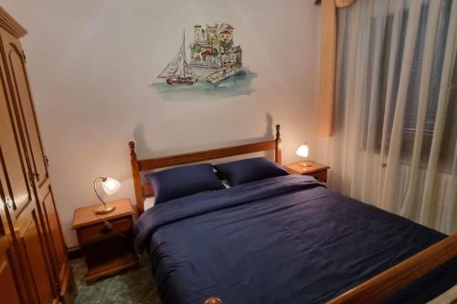 洛克维APARTMENT GORDANA A4+2 FOR 6 PAX NATURE PARK的一间卧室配有一张带蓝色床单的床和墙上的绘画。