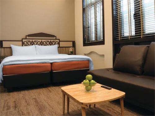 新加坡Aqueen Prestige Hotel Lavender的一间卧室配有一张床、一张沙发和一张桌子