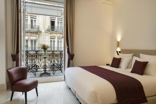 巴黎Vestay Montaigne的一间卧室设有一张床、一个窗口和一把椅子