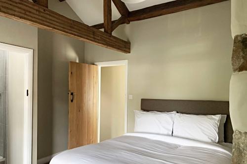 哈利法克斯Croft House Cottage的卧室设有白色的床和木制天花板。