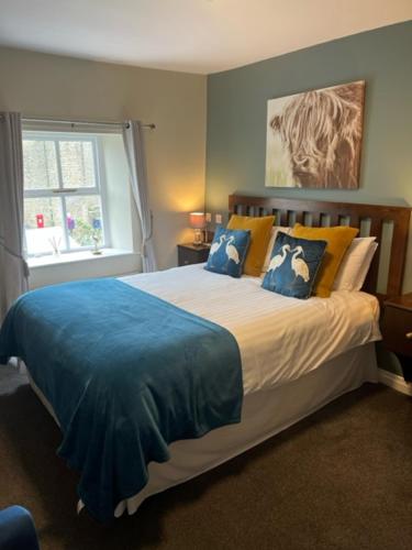 哈德斯菲尔德玫瑰和皇冠酒店的一间卧室配有一张带蓝色床单的大床和窗户。