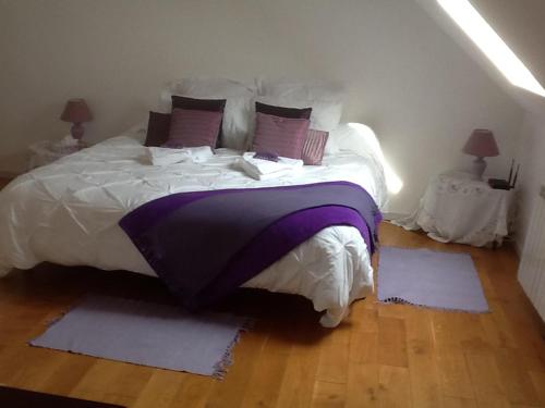 KérienCaptivating 2-Bed House with log burner in Kerien的一间卧室配有一张大床,提供紫色床单和枕头