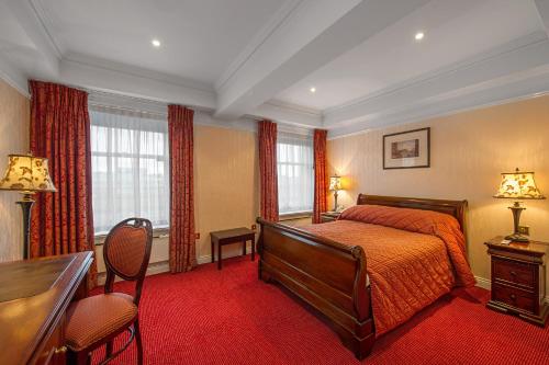 都柏林永利酒店的一间卧室配有一张床、一张书桌和两个窗户。