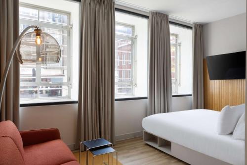 鹿特丹Motto By Hilton Rotterdam Blaak的酒店客房带一张床、椅子和窗户