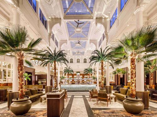 利物浦The Municipal Hotel Liverpool - MGallery的酒店大堂种植了棕榈树,设有酒吧