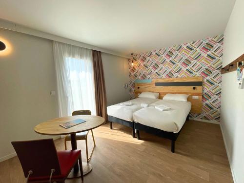 卡斯泰greet hotel Castets Coeur des Landes的酒店客房,配有床、桌子和桌子。