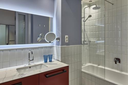 布拉格Falkensteiner Boutique Hotel Prague的浴室配有水槽、淋浴和浴缸。