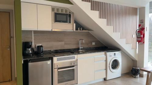乌斯怀亚Miras Apartment Ushuaia的厨房配有洗衣机和烘干机,位于楼梯下