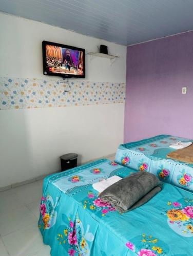 贝伦Hostel das Flores的客房设有一张带蓝色毯子的床和一台电视。