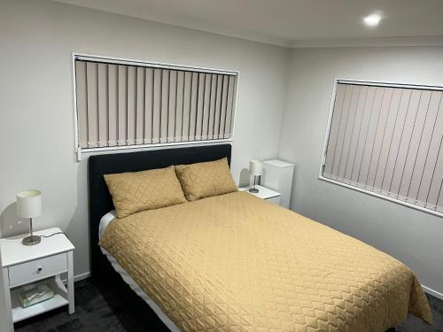 奥克兰Private resident的一间卧室配有一张带黄色床罩的床和两个窗户