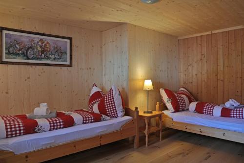 圣安特尼恩Gasthaus Bellawiese的客房配有两张带红白色枕头的床。
