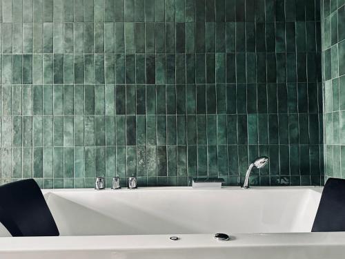 哥德堡斯巴尔加尔达酒店的浴室铺有绿色瓷砖,配有浴缸。