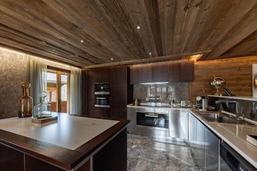 格施塔德Ultima Gstaad Residences的大型厨房设有木制天花板和台面