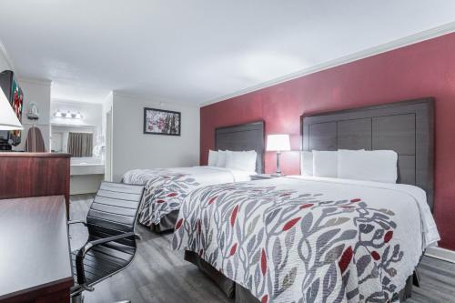 福雷斯特城Red Roof Inn Forrest City的酒店客房设有两张床和红色的墙壁。