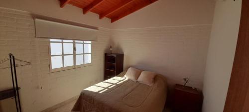 玛德琳港Los Choiques Madryn的一间卧室设有一张床和一个窗口