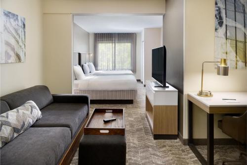 达拉姆罗利达拉姆机场/三角研究园春季山丘套房的一间客厅,客厅配有沙发和一张位于酒店客房内的床