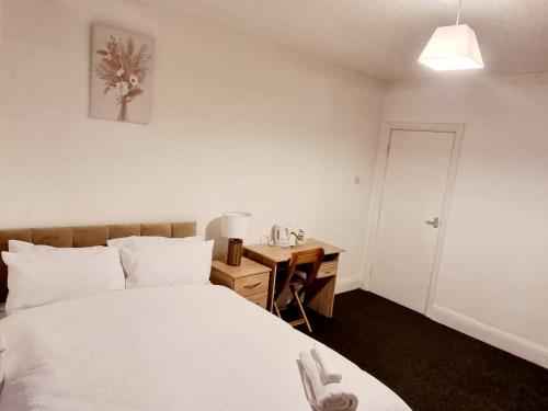BalbyLilies Lodge的卧室配有白色的床和带台灯的书桌