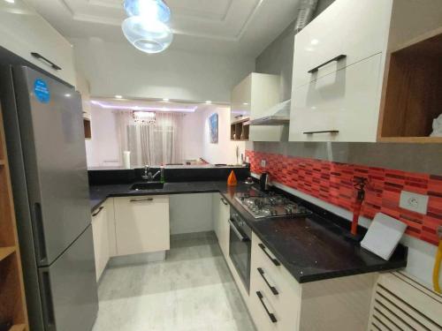 Le KramDar Al Yaqout的厨房配有白色橱柜和黑色台面