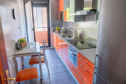 索托德拉马里纳Piso nuevo cerca de Santander的厨房配有橙色和灰色的橱柜和桌子