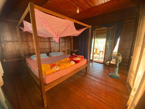 Phumĭ PôyBanlung Hill Top House &Trekking的卧室配有一张位于房子内的天蓬床