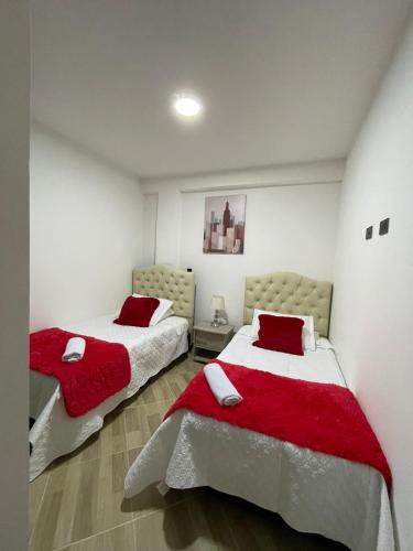 圣罗莎德卡瓦尔Moderno apto familiar piso 2的白色客房的两张床,配有红色枕头