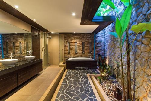 拉威海滩隐藏泳池别墅的浴室配有2个盥洗盆、浴缸和淋浴。