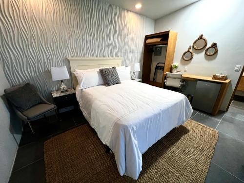 BonitoVillas Quijote Valle de Guadalupe的卧室配有白色的床和椅子