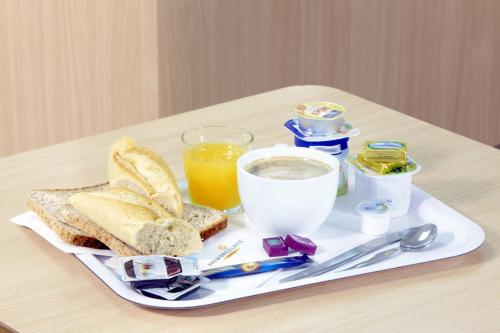 贝济耶普瑞米尔克拉斯贝兹尔酒店的早餐盘包括面包、烤面包和一杯橙汁