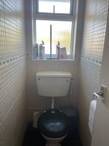 特威克纳姆Cozy Home的浴室设有卫生间、黑色座椅和窗户。