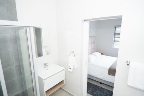 SandtonStylish Apartment in Fourways的带淋浴和盥洗盆的浴室以及1张床。