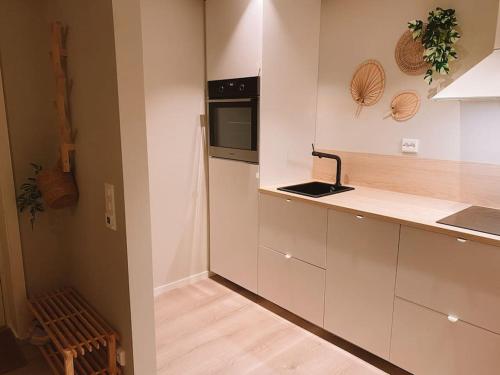 克里斯蒂安桑Cute little appartment的厨房配有白色橱柜和黑微波炉